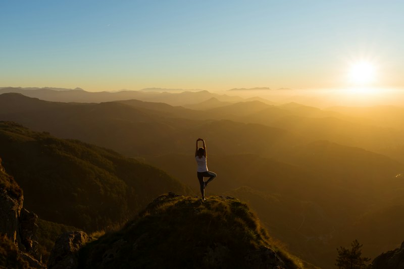 Person auf einem Berggipfel im Sonnenaufgang