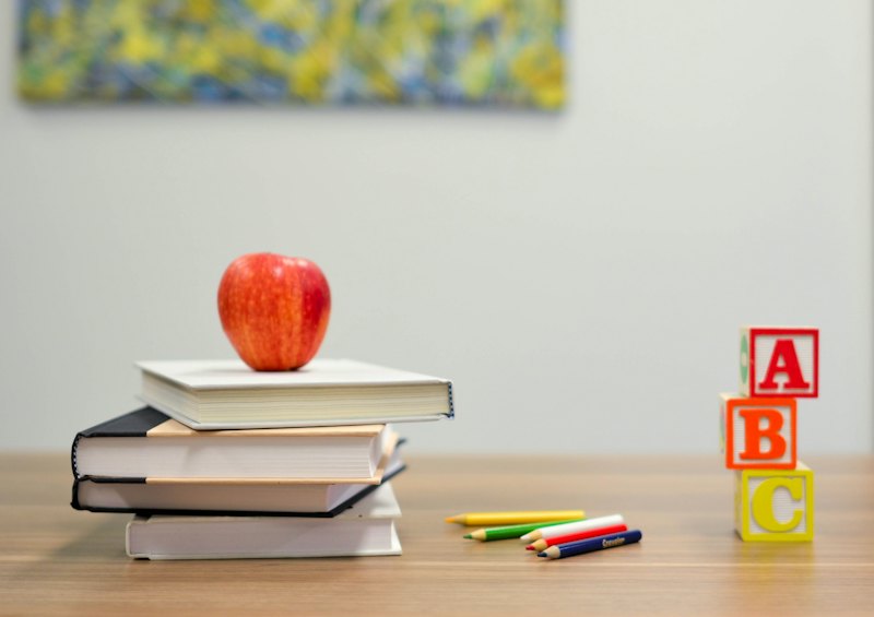 Bücher, Apfel und Buchstabenwürfel auf einem Tisch